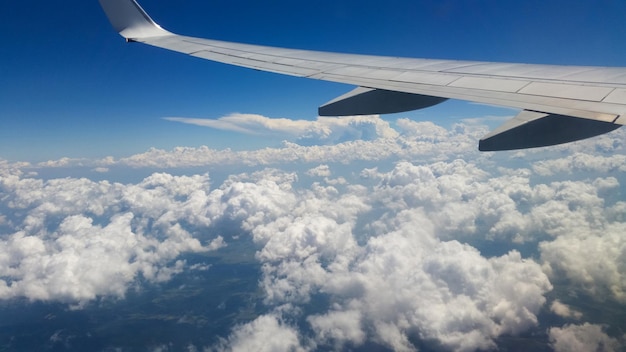 Schöne dicke Wolken am Himmel aus der Flughöhe des Flugzeugs mit Blick auf den Flügel mit Triebwerken