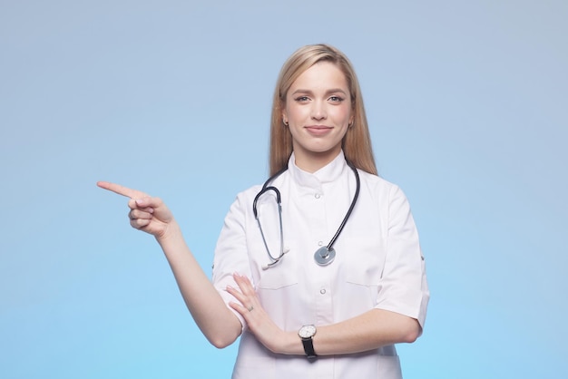 Schöne Doktordame, die mit der Hand auf den Kopienraum zeigt Studioaufnahme isoliert auf grauem Hintergrund