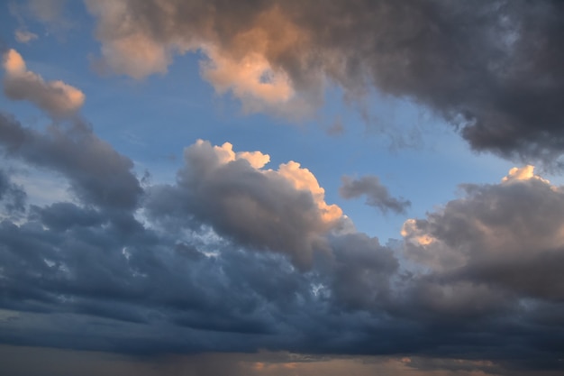 Schöne dramatische Wolkenlandschaft des frühen Sonnenuntergangs mit flauschigen beleuchteten beleuchteten Wolken über klarem blauem Himmel, Ansicht des niedrigen Winkels