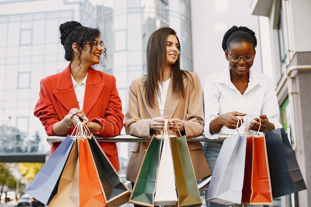 Schöne drei junge Frauen mit Geschenktüten gehen in die Stadt. Frauen nach dem Einkaufen haben Spaß.