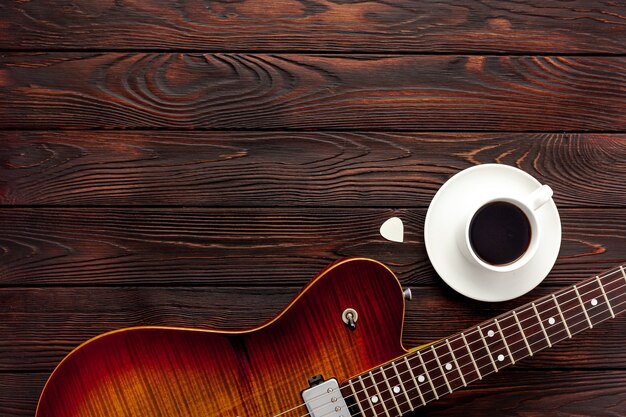 Schöne E-Gitarre mit Kopfhörern und Kaffee-Desktop