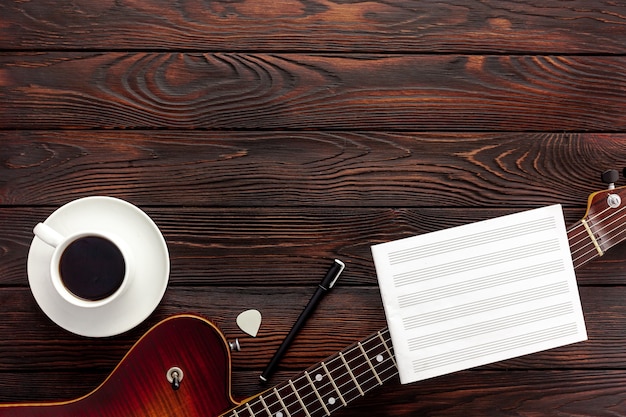 Schöne E-Gitarre mit Kopfhörern und Kaffee-Desktop