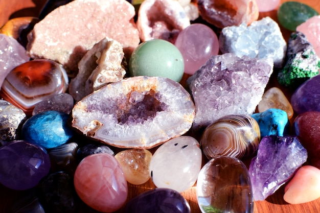Schöne Edelsteine, Geode-Amethyst und Drusen aus natürlichem violettem Mineral-Amethyst auf Holzhintergrund. Amethyste und Rosenquarz. Große Kristalle aus Halbedelsteinen.