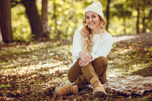 Schöne elegante Frau, die in einem Park im Herbst steht.