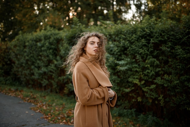 Schöne elegante Frau, die in einem Park im Herbst steht