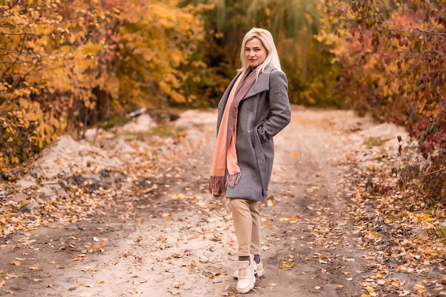 Schöne elegante Frau, die in einem Park im Herbst steht