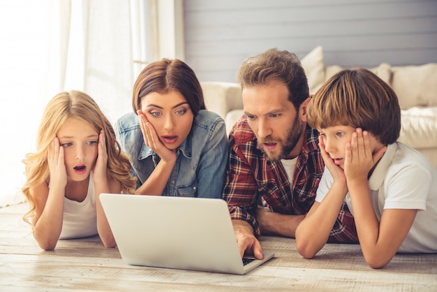 Schöne Eltern und ihre Kinder benutzen einen Laptop.