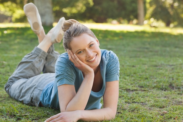 Foto schöne entspannte frau, die auf gras am park liegt