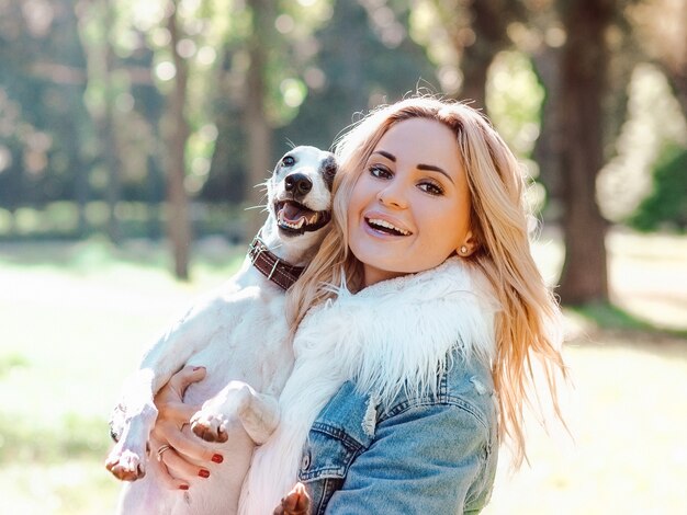 schöne entzückende glückliche blonde Besitzerin mit ihren zwei weißen Whippet im Freien