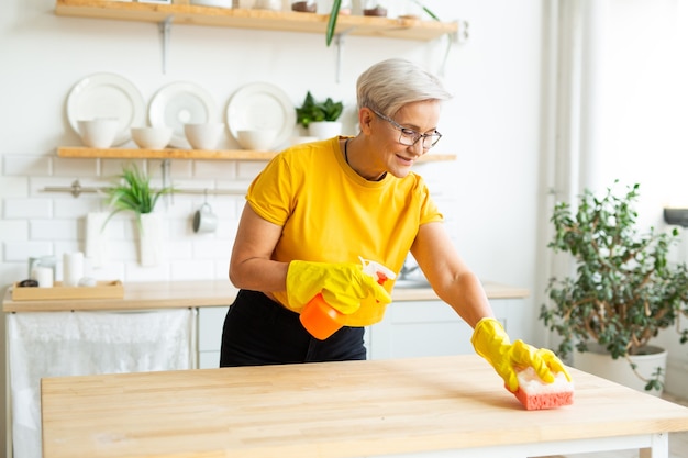 schöne erwachsene Frau mit Brille in einem gelben T-Shirt macht Hausreinigung