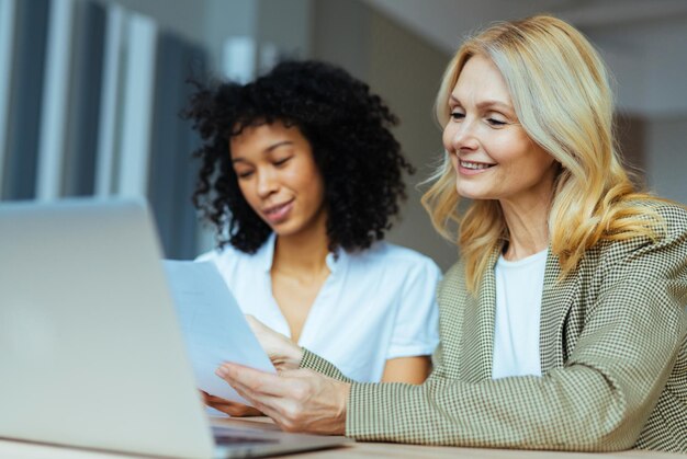 Schöne erwachsene Geschäftsfrauen mit elegantem Kleid, die am Computertisch im Büro sitzen