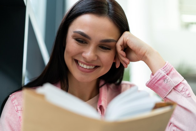 Schöne erwachsene Studentin, die eine Pause in der Universitätsbibliothek verbringt, während sie nach dem notwendigen Literaturunterricht sucht Studienkonzept