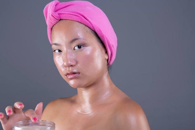 Schöne ethnische Chinesin, die sich mit Gesichtscreme um ihr Gesicht kümmert