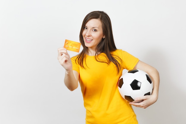 Schöne europäische junge fröhliche Frau, Fußballfan oder Spieler in gelber Uniform mit Kreditkartenfußball isoliert auf weißem Hintergrund. Sport, Fußballspiel spielen, Lifestyle-Konzept der Aufregung.