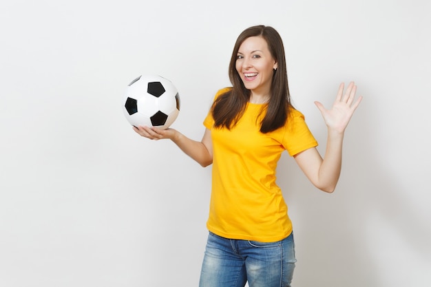 Schöne europäische junge fröhliche glückliche Frau, Fußballfan oder Spieler in gelber Uniform, die Fußball isoliert auf weißem Hintergrund hält. Sport, Fußball spielen, Gesundheit, gesundes Lebensstilkonzept.