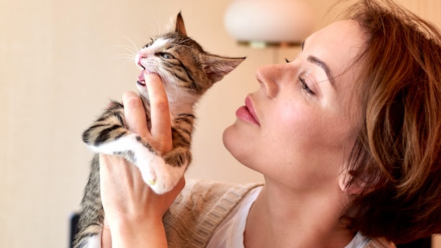 Schöne fällige Frau, die mit einer kleinen Katze spielt