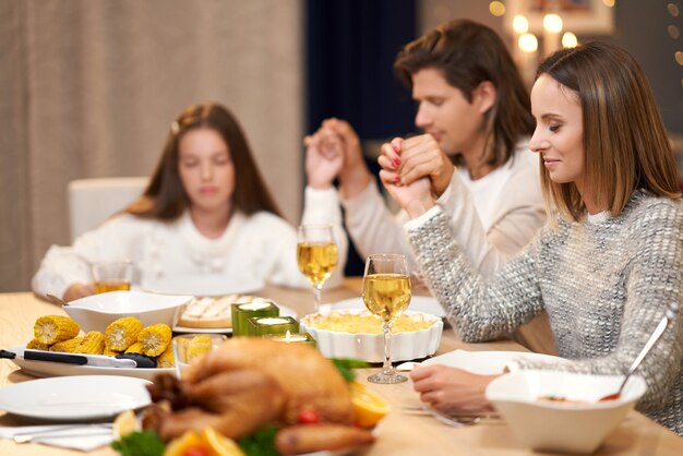 schöne Familie, die beim Feiertagsessen betet