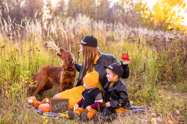 Schöne Familie mit einem Golden Retriever Hund auf einem Spaziergang in der sonnigen Natur des Herbstes