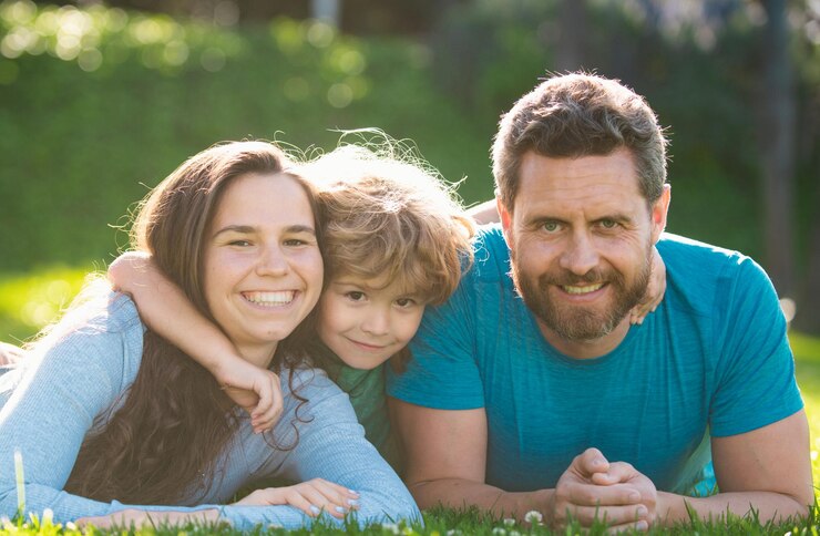 Foto schöne familienporträt umarmt und umarmt familie liegt auf dem gras im park eltern und kinder auf