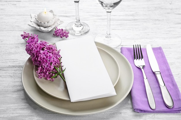 Schöne festliche Tischdekoration mit lila Blumendekor auf Holzhintergrund