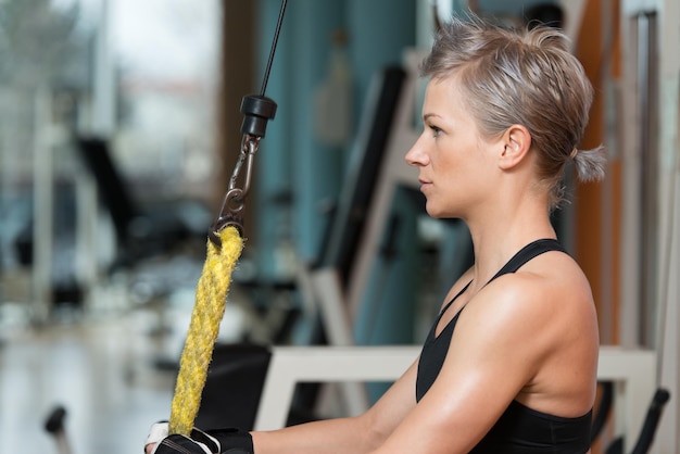 Schöne fitte Frau trainiert Trizeps im Fitnessstudio