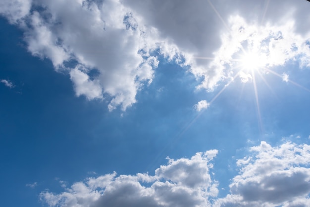 Schöne flauschige weiße Wolken des Kumulus auf einem blauen Himmel mit heller Sonne. Perfekter abstrakter Himmelshintergrund, Tapete, Layout