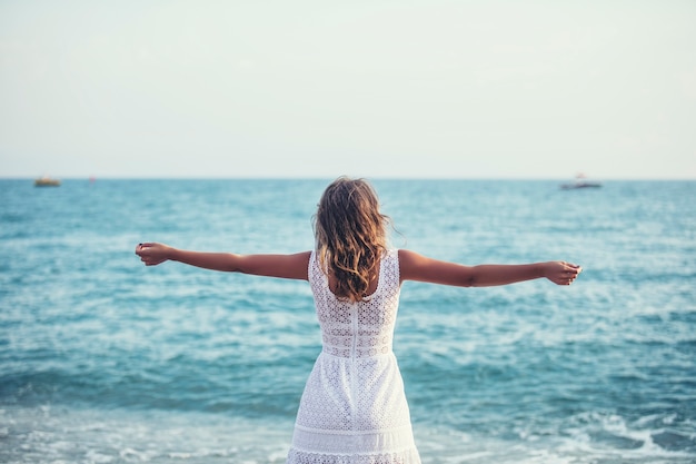 Schöne Frau am Strand in einem weißen Kleid glücklich entspannend