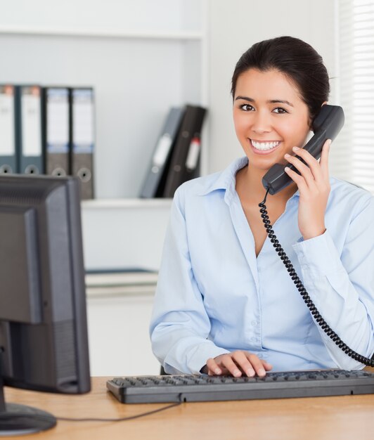 Schöne Frau am Telefon beim Tippen auf einer Tastatur