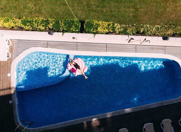 Schöne Frau auf Flamingo-Pool-Schwimmer im Pool im Hotel, Drohnen-Luftbild