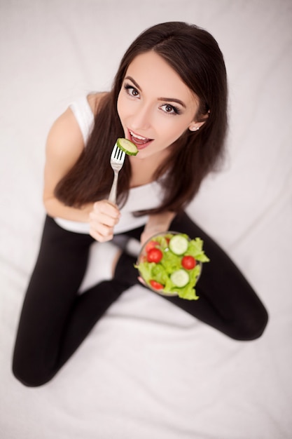 Schöne Frau auf gesunder Ernährung mit grünem Bio-Gemüsesalat in der Küche