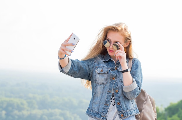 Schöne Frau auf Reisen, die Selfies in den Bergen macht. Sommer, Technologie, Fotokonzept