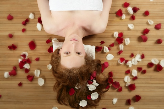 Schöne Frau des Redhead, rosafarbene Blumenblätter auf Haar