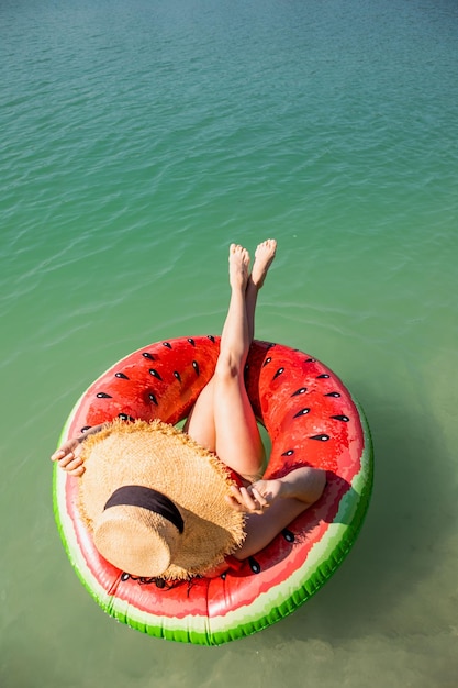 Schöne Frau, die auf aufblasbarem Ring im blauen Seewasser schwimmt