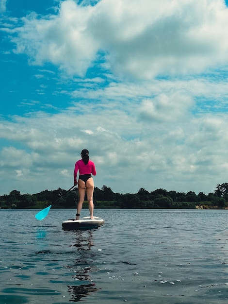 Schöne Frau, die auf dem Supboard steht, hält das Gleichgewicht