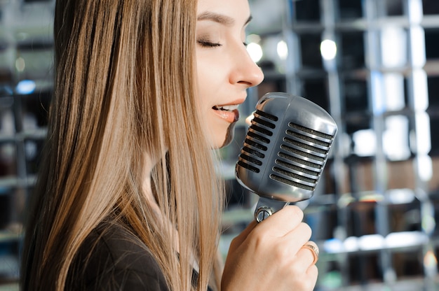 Schöne Frau, die auf der Bühne neben dem Mikrofon singt.