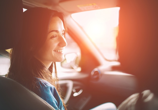 Schöne Frau, die beim Sitzen auf dem Rücksitz im Auto lächelt.