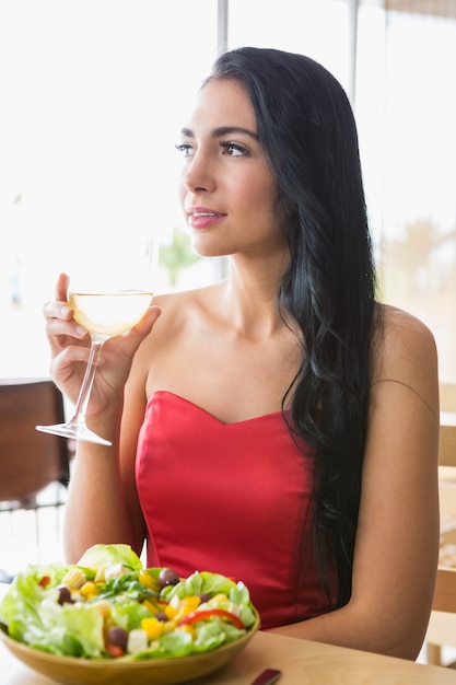 Schöne Frau, die Champagner mit Salat hat