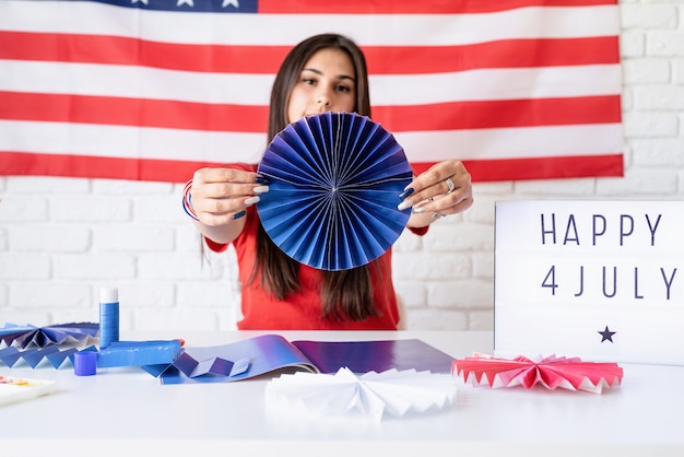 Schöne Frau, die DIY-Papierrosetten der roten und blauen Farben macht, um 4. Juli zu feiern