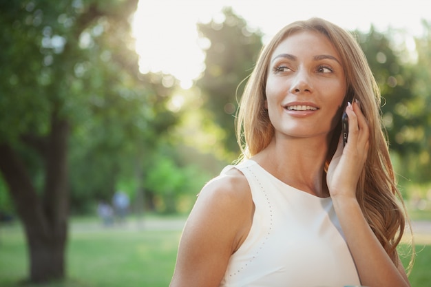 Schöne Frau, die draußen am Telefon spricht