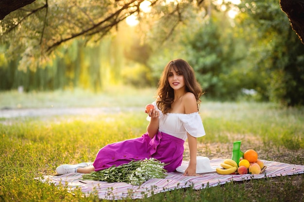 Schöne Frau, die draußen ein Picknick genießt Picknick für einen