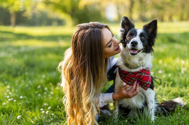 Schöne Frau, die draußen in der Natur mit süßem Hund spielt