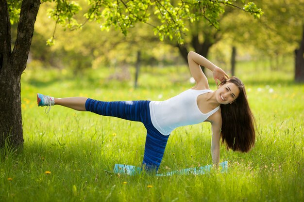 Schöne Frau, die draußen trainiert. Nettes dünnes Mädchen, das Training am Park in der Sommerzeit tut