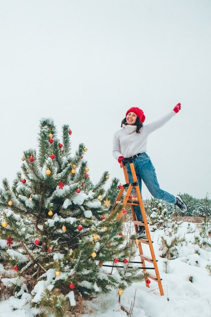 Schöne Frau, die draußen Weihnachtsbaum schmückt