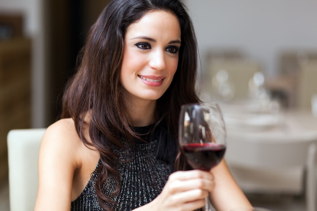 Schöne Frau, die ein Glas Rotwein anhält