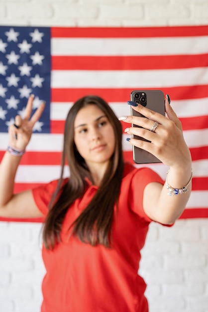 Schöne Frau, die ein selfie auf dem USA-Flaggenhintergrund nimmt