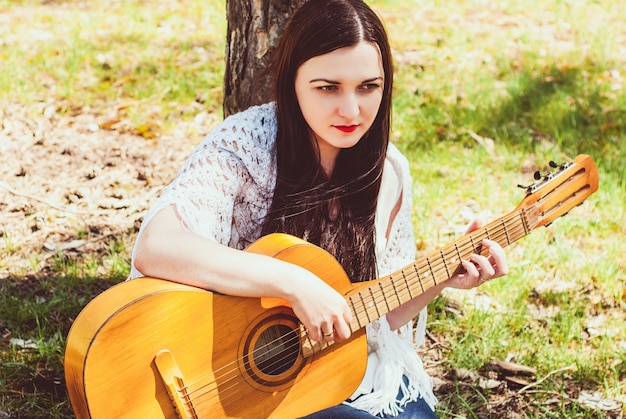 Schöne Frau, die eine Akustikgitarre im Freien spielt