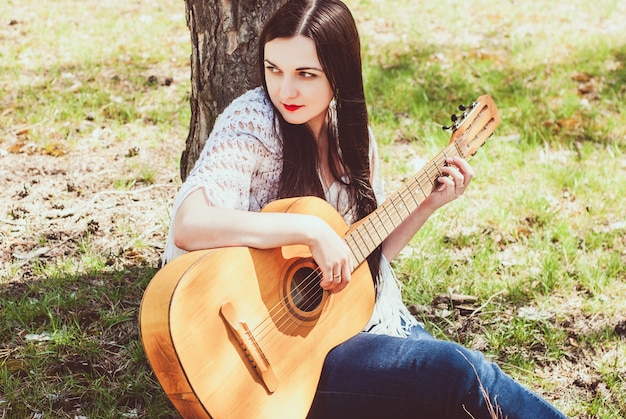 Schöne Frau, die eine Akustikgitarre im Freien spielt