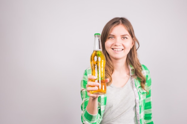 Schöne Frau, die eine Flasche Bier hält. Hintergrund mit Kopienraum.