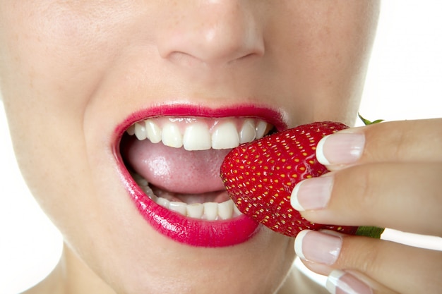 Schöne Frau, die eine rote Erdbeere isst
