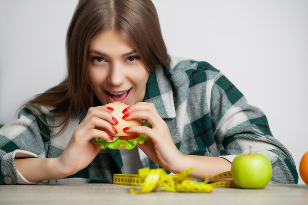 Schöne Frau, die eine Wahl zwischen nützlichem und schädlichem Essen trifft